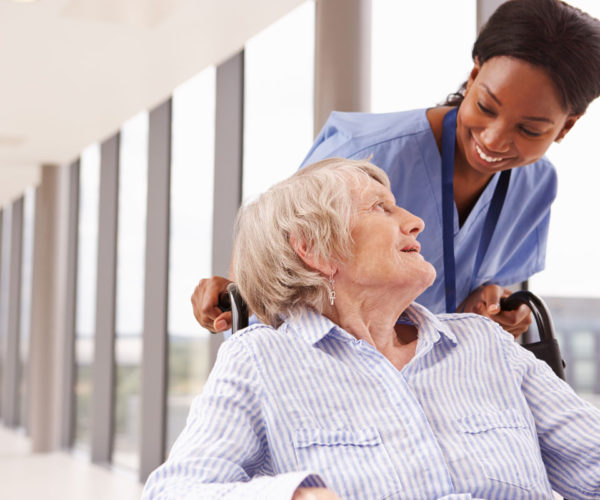 A senior in wheelchair smiling at a nurse
