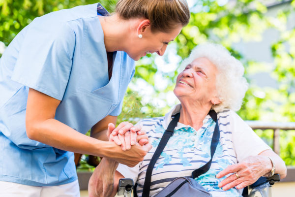 Woman speaking to elderly woman and holding her hand