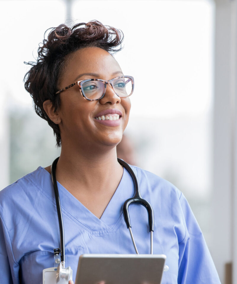 Beautiful nurse smiles while holding digital tablet